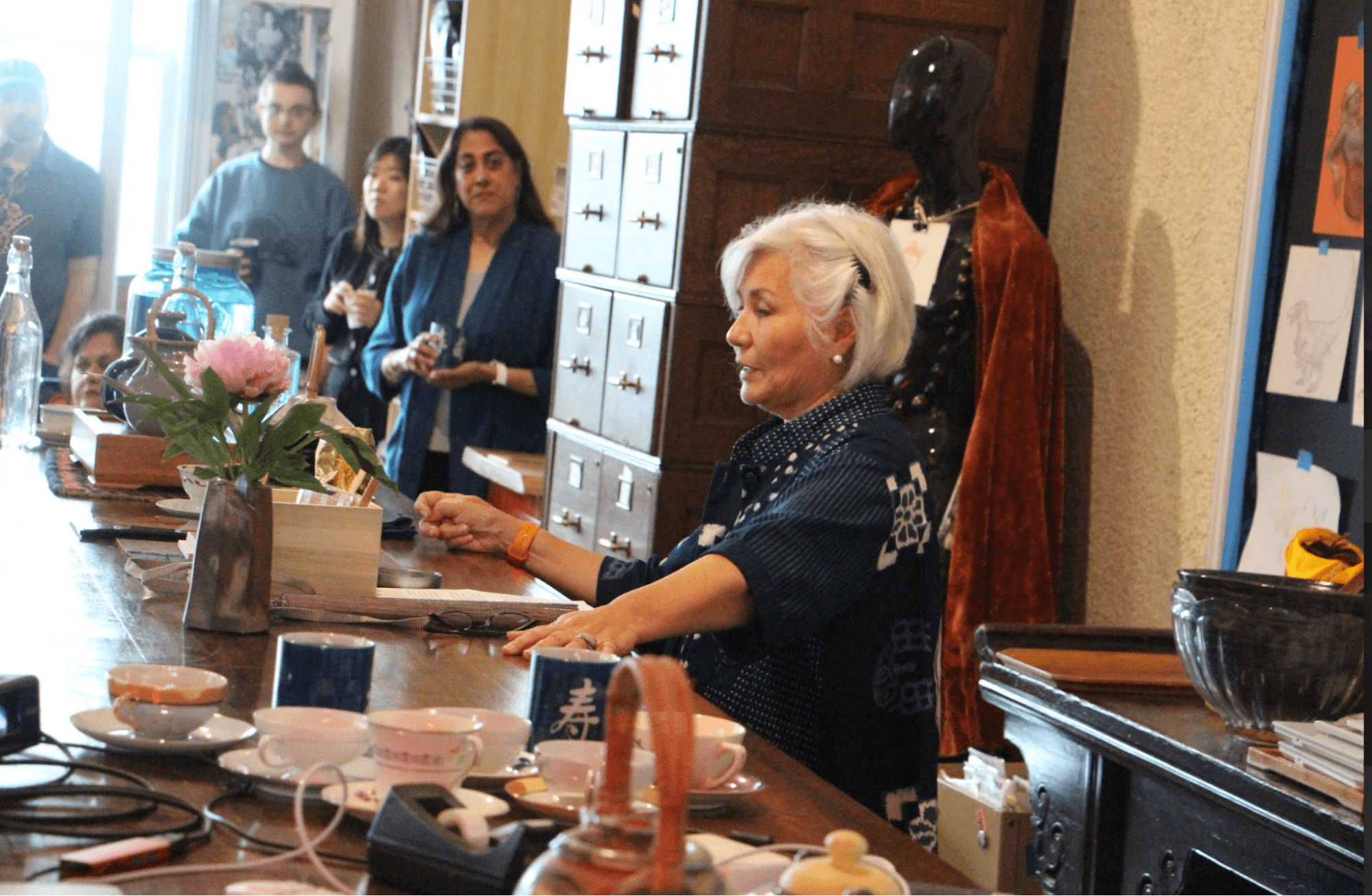 Woman with gray hair facilitating a tea ceremony